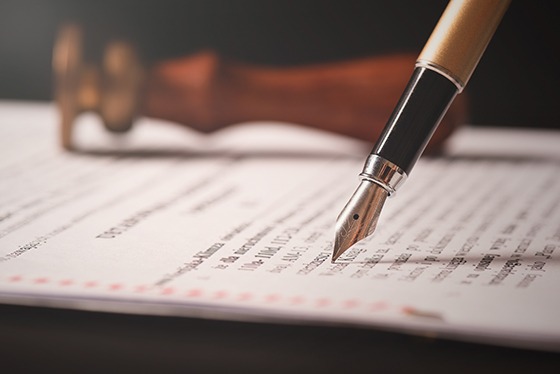 A pen, stamp, and legal paperwork on a table.